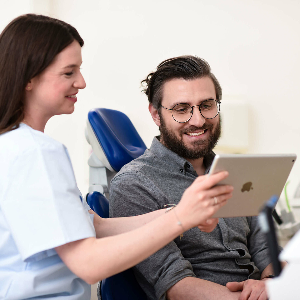 Unsere Zahnärztin in unserer Wiesbadener Zahnarztpraxis klärt einen Patienten über unsere Behandlungsmethoden auf